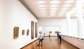 The floor of the gallery room with visitors in front of artworks on the wall